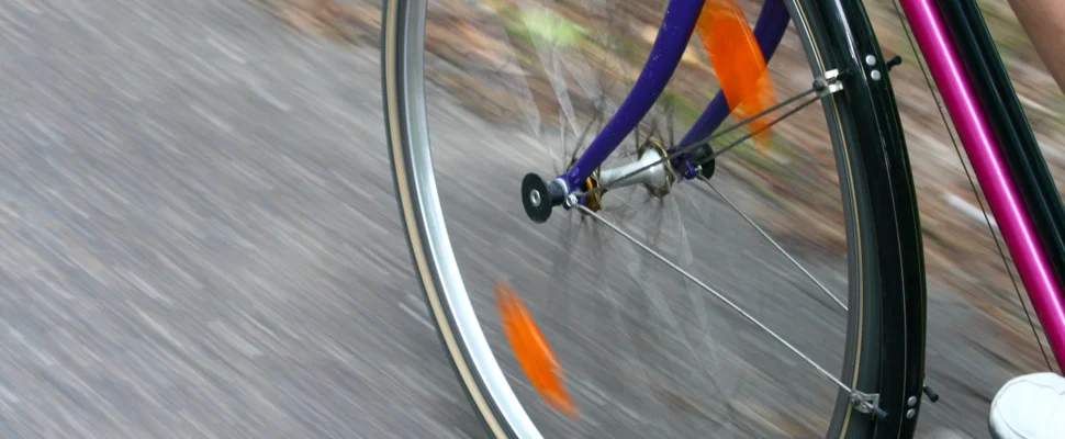 Framdäcket på en cykel. Asfalten är i oskärpa vilket visar att cykeln är i fart.