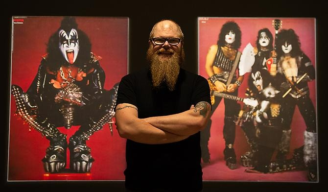 Foto av Alexander Johansson framför två affischer på rockgruppen KISS. väggen bakom är röd.  